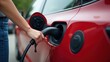 © rahwik - Crop Female Inserting Charger into Red Electric Car at EV Charging Station