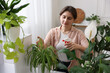 © New Africa - Woman spraying beautiful potted houseplant with water indoors