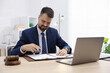 © New Africa - Notary stamping document at wooden desk in office