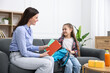 © New Africa - Mother and daughter packing backpack for school on sofa at home