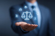 © Ahmar Stock - a businessman holding out his hand with an icon of the scales of justice and other business icons floating above it.