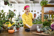 © Sofiia Shunkina - A woman in a yellow shirt holds a succulent while working on a laptop in a plant shop