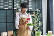 © Charlie's - Asian Male Small Business Owner of Eco-Friendly Plant Shop Using Smartphone to Live Stream and Promote Sustainable Greenery Online with Modern Digital Technology.