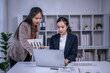 © Apichat - Businesswomen collaborating on financial data using a laptop