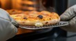 © Nataly - Fresh pizza with golden crust removed from hot oven using insulated mitts and rack. Hot fresh pizza features bubbling cheese and slightly charred edges, releasing steam.