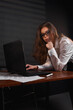 © Dmitriy - Elegant woman in white shirt and black skirt posing near desk table on the office background.
