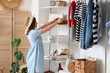 © Pixel-Shot - Young woman taking organizer from shelf in wardrobe