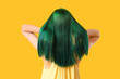 © Pixel-Shot - Young woman with green hair on yellow background, back view