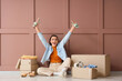 © Pixel-Shot - Happy young woman with shoes and wardrobe boxes sitting near brown wall
