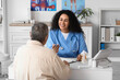 © Pixel-Shot - Young African-American doctor working with senior woman at table in clinic
