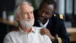 © Denis Yevtekhov - African American military man in uniform supporting sad Caucasian white veteran friend in wheelchair, group therapy psychological session, veterans mental health togetherness, defocused
