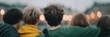 © misunderst00d - Rear view of group of young friends walking together with arms around each other's shoulders outdoors at dusk, with blurred bokeh lights in background