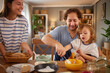 © Stockphotodirectors - A family laughs and enjoys each other's company while preparing a delicious recipe in their warm and inviting kitchen. The atmosphere is filled with joy and togetherness.