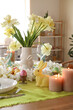 © Pixel-Shot - Festive table setting decorated with spring flowers, candles and Easter bunnies in kitchen