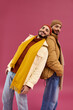 © LIGHTFIELD STUDIOS - Stylish twin brothers pose playfully against a vibrant pink backdrop in modern attire