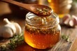 © Vira - Close-up of a wooden spoon dipping into a jar of infused honey (garlic and herb), immune booster