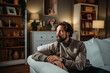 © Dusan - Thoughtful man sitting on sofa in cozy living room
