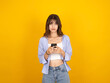 © Designerant - Bored frustrated woman, portrait of young caucasian beautiful bored frustrated woman 20s hold use mobile phone reading unpleasant news messages standing over yellow studio background, copy space.