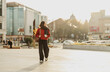 © olezzo - Smiling young woman walking down the sunny European street with cup of coffee to go