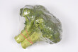 © nahhan - High angle shot of a fresh green broccoli head wrapped in clear plastic film with a red rubber band on a plain white background.