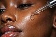 © Asfand - Close up of black woman applying facial serum with pipette on glowing hydrated skin