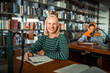 © Marko Geber - Smiling student studying at table in library