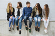 © anatoliycherkas - Group of diverse teenagers sitting together, laughing and talking outdoors, celebrating youth, friendship, and connection