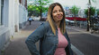 © Krakenimages.com - Woman hands on hips wearing denim jacket and pink shirt on street, smiling at camera; confidence ease.
