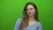 © Krakenimages.com - Woman wearing blue top scowls with pouty lips and long hair and turns head sideways in green studio; disgust.