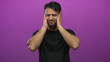 © Krakenimages.com - Young hispanic man holding head in frustration over isolated purple background wearing black shirt displaying stress and discomfort