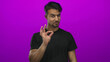 © Krakenimages.com - Young hispanic man makes an okay gesture pointing to the side against an isolated vibrant pink background, conveying positivity and direction.