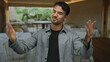 © Krakenimages.com - Young man in a restaurant smiling confidently with arms open, creating a welcoming atmosphere in a cozy indoor dining setting.