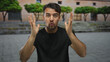 © Krakenimages.com - Young hispanic man gesturing passionately outdoors in front of blurred urban backdrop with trees and building creating an expressive yet frustrated look as he talks to the camera.