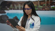 © Krakenimages.com - Scientist woman in uniform working on tablet by outdoor pool at resort hotel showcasing innovation in a unique setting with a modern twist on traditional research environments.