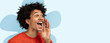 © Prostock-studio - A young man stands smiling and shouting, expressing excitement. He has curly black hair and wears a red shirt. The background is light blue with flower shapes. The moment shows happiness and energy.