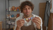 © Krakenimages.com - Man in apron holding small ceramic glaze pots with both hands in a pottery studio; quiet contemplation craft.