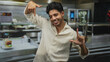 © Krakenimages.com - Man smiling and framing with fingers beside plated burger on stainless counter in kitchen inside building; playful confidence.