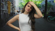 © Krakenimages.com - Woman in white tank top hand on head gesture on bustling city street at daytime with blurred buildings; confusion.