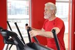 © New Africa - Senior man training on elliptical machine in gym