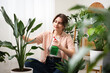 © New Africa - Woman spraying beautiful potted houseplant with water indoors