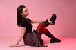 © New Africa - Beautiful young woman with piercings in stylish skirt and boots posing in red light on pink background