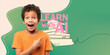 © Prostock-studio - A young boy with curly hair shows excitement while pointing to the side. He wears a t-shirt and stands against a blue backdrop, celebrating a moment of discovery in a learning environment.