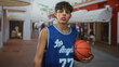 © Krakenimages.com - Boy holding a basketball with hand at his side on a shopping street wearing a los angeles jersey; youthful determination.