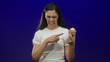 © Krakenimages.com - Young woman in white shirt grimaces as she points finger to freshly baked muffin in deep blue studio; disgust.