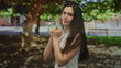 © Krakenimages.com - Woman punches with clenched fists in a sunlit lush green park amid broad tree canopy; determination.