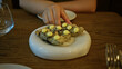 © Krakenimages.com - Woman hands placing fried appetizer topped with yellow sauce dollops on white ceramic plate in restaurant interior; anticipation.
