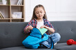 © New Africa - Girl packing her backpack for school on sofa at home