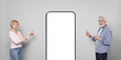 © New Africa - Senior couple pointing at big smartphone with blank screen on grey background