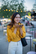 © Laingzaifa - An Asian woman is strolling through a night market, enjoying traditional street food, colorful lanterns, and smiling at the bustling city stalls. It's a vibrant atmosphere and a wonderful cultural