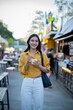 © Laingzaifa - Asian women enjoy delicious street food at night markets, smiling throughout their vacation, exploring the city's culture, vibrant lights, and fun-filled adventures.